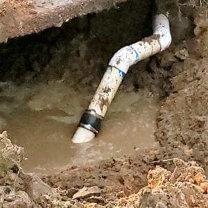 Image of a 4" sewer line repair performed by Honey Bee Plumbing under the edge of a driveway at a Pensacola, Florida home.